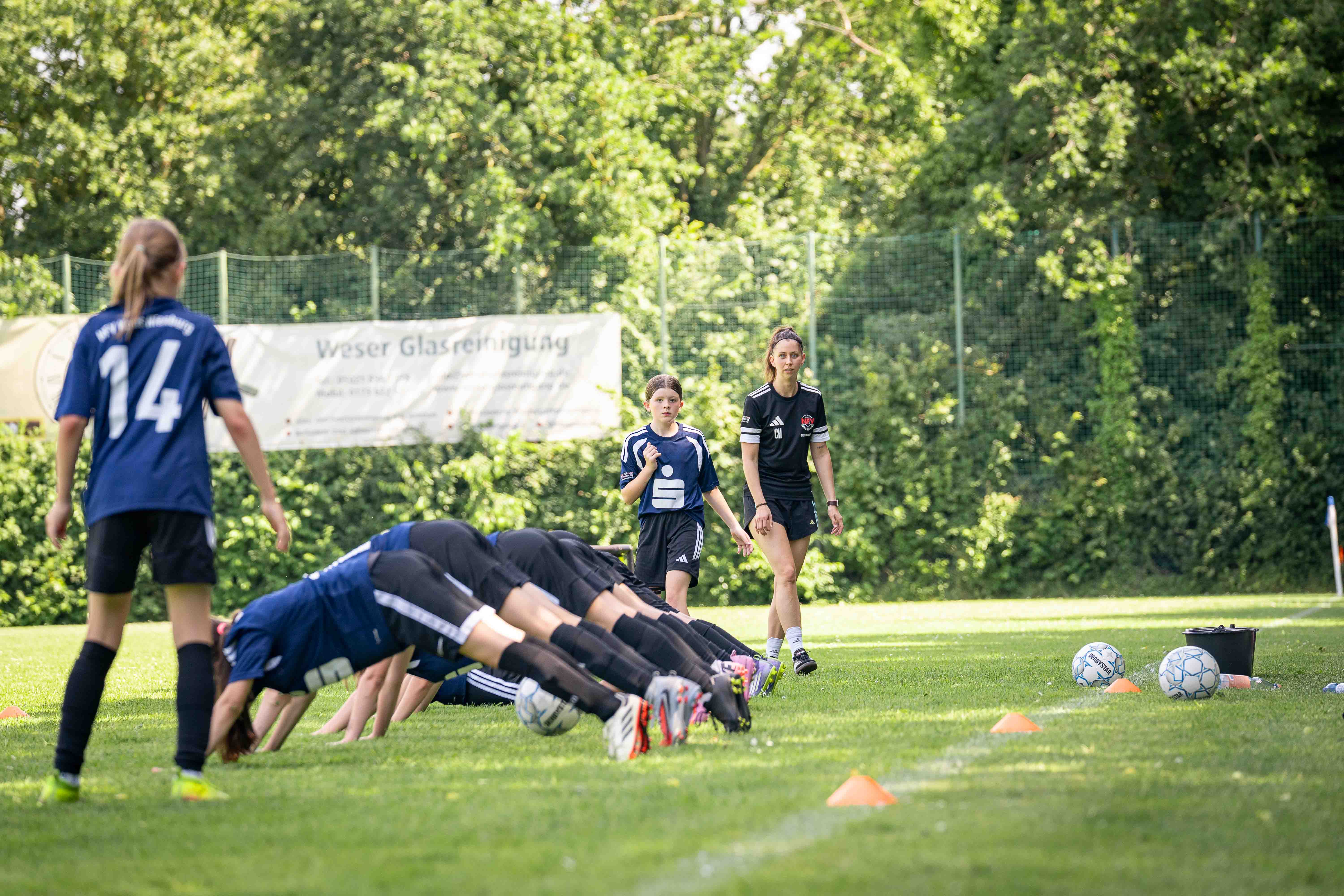 Eien Spielerin spielt den Ball durch die sich in der Liegestütz befindenen restlichen Mannschaft
